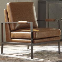 a brown leather chair sitting on top of a rug next to a metal cabinet and lamp