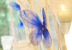 a blue butterfly sitting on top of a window sill next to a vase filled with flowers