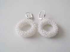 two pairs of white beaded earrings on a white surface