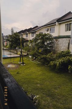 an empty yard in front of some houses with trees on the other side and grass growing all around