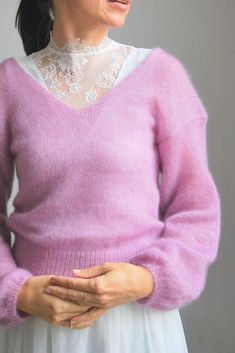 an older woman wearing a pink sweater and white skirt with her hands in her pockets