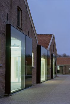 an empty street lined with brick buildings next to tall glass windows on each side of the building