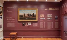 a room with purple walls and pictures on the wall, along with a wooden bench