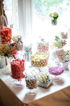 a table topped with lots of candy and candies next to a window filled with flowers