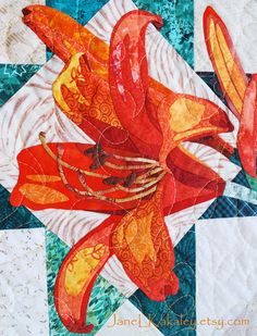 an orange flower is on top of a quilt