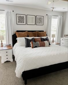 a white bed sitting in a bedroom next to two windows