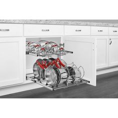 an open dishwasher in a kitchen with white cabinets and red handles on the doors