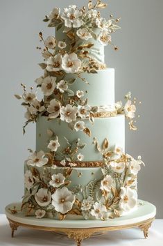 a three tiered cake with white flowers on top and gold trim around the edges