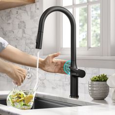 a woman is washing her hands under the faucet in the kitchen sink,