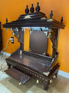 an ornate wooden table with mirror and shelf on wheels in front of a yellow wall