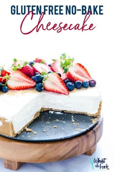 a cheesecake with strawberries and blueberries is on a wooden platter that says gluten free no - bake cheesecake