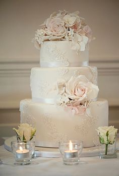 a wedding cake with white flowers and candles