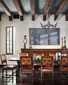 a dining room table with chairs and a chalkboard on the wall