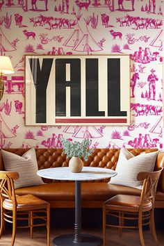 a living room filled with furniture and a wall covered in pink stencils that says y'all