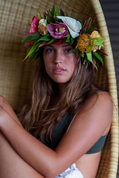 a woman sitting in a chair wearing a flower crown on top of her head,