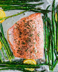 salmon and asparagus on foil with lemons, parsley and seasoning