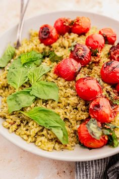 a white bowl filled with rice and tomatoes on top of a marble table next to a fork