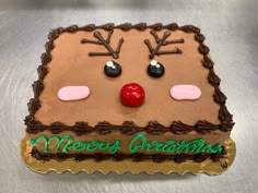 a decorated christmas cake with chocolate frosting and reindeer's noses on it, sitting on a table