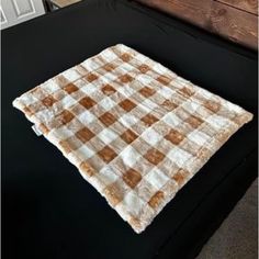 a black bed with a brown and white checkered blanket on it's side