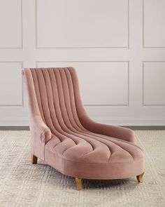 a pink chair sitting on top of a rug in front of a white paneled wall