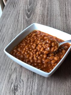 a white bowl filled with baked beans on top of a wooden table