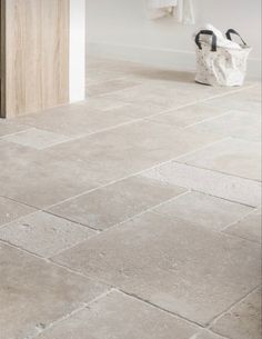 a white bathroom with grey tile flooring next to a door