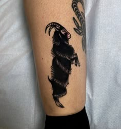 a black and white photo of a goat tattoo on the leg