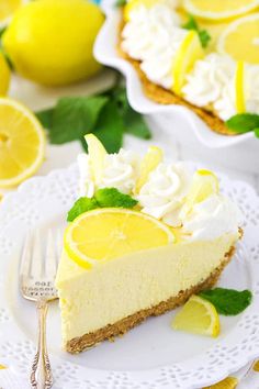 a slice of lemon pie on a plate with a fork next to it and some lemons in the background