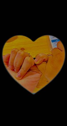 two hands holding each other in front of a heart shaped photo on a black background