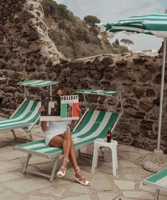 a woman sitting on top of a lawn chair holding a box with the word holiday written on it