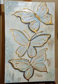 a painting with gold and blue butterflies on it's back side, in the process of being painted