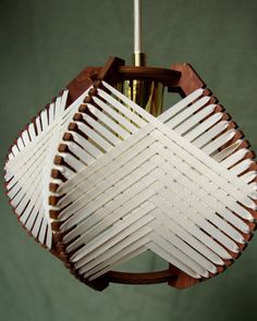 a light fixture made out of wood and white strips on the top, with a green wall in the background