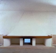 a white wall with a wooden bench in the center and tile on the floor below