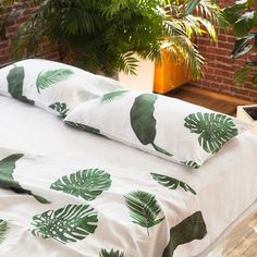 a bed with green leaves on it in front of a brick wall and potted plants