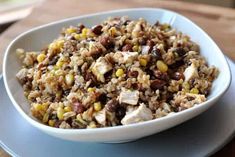 a white bowl filled with rice and beans on top of a blue plate next to a wooden table