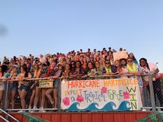 a large group of people standing on top of a metal fence next to each other