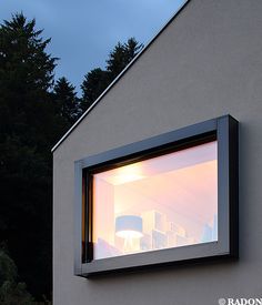 an open window on the side of a white building with trees in the back ground