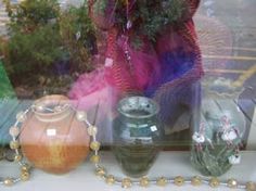 there are many vases on display in the window sill, including one with a beaded necklace