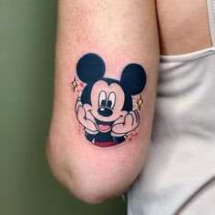 a woman's arm with a mickey mouse tattoo on the left side of her body