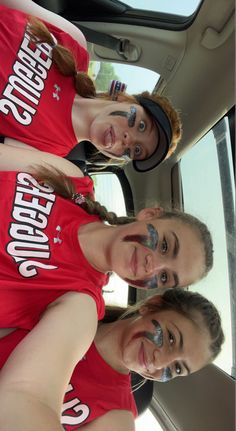 three girls in red shirts standing next to each other near the back door of a car