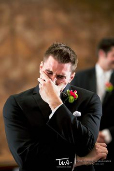 a man in a tuxedo covers his face with his hands while another man looks on