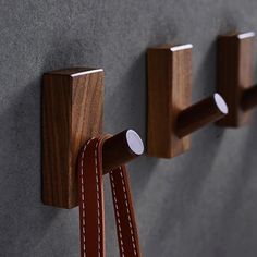 three pieces of wood are hanging on the wall with leather straps attached to each piece