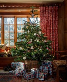 a christmas tree with presents under it in front of a window