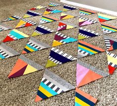 colorful paper triangles laid out on the floor in front of a wall and carpeted area