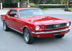 an old red mustang sitting in a parking lot