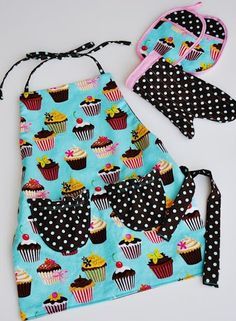 an apron, hat and bib are shown with cupcakes on blue fabric