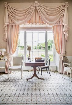 a living room filled with furniture and a window covered in pink drapes next to a table