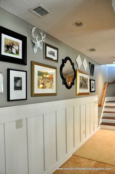 there are many pictures hanging on the wall next to the stairs in this house, including deer heads and antlers