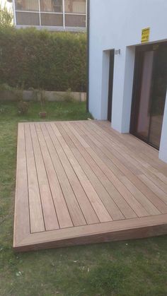 a wooden deck in front of a white building with sliding glass doors on the side