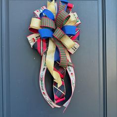 a colorful bow hanging on the side of a gray door with blue, red and yellow ribbons